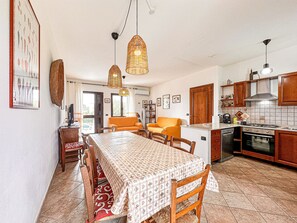 Un coin repas avec une table dressée pour quatre personnes, une cuisine avec des meubles en bois et une chaise de salle à manger visible.