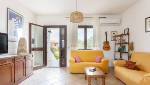 A living room with a sofa, a coffee table, a television, a guitar, and a bookshelf. - Holiday Home 'Santa Caterina' with Mountain View, Wi-Fi and Air Conditioning (Santa Caterina di Pittinuri)