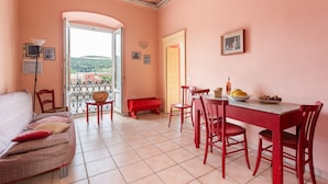 Ein Zimmer mit einer Couch, einem Esstisch, Stühlen und einem Balkon mit Blick.