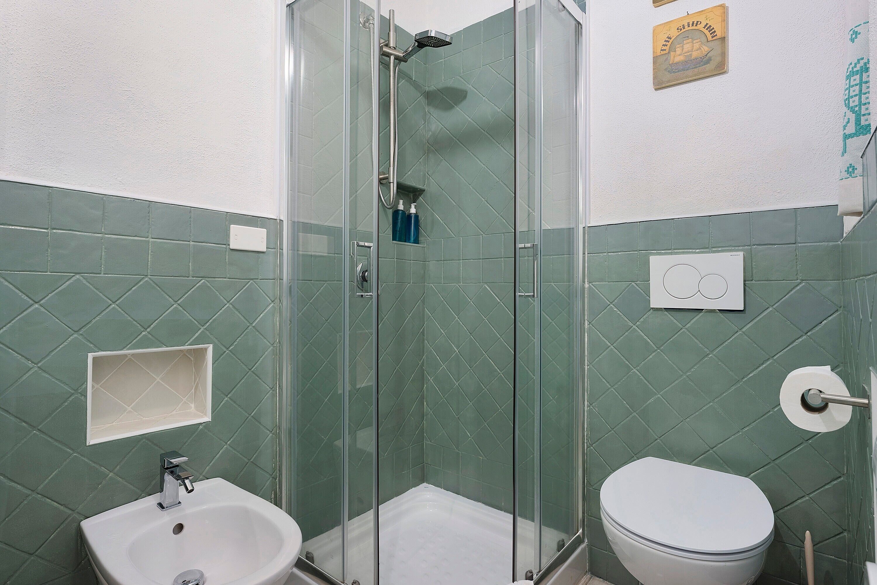 Un bagno con doccia vetro, lavabo bianco e WC.