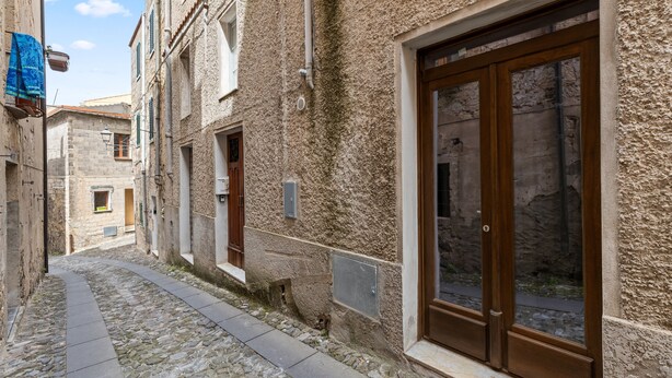 Una estrecha calle adoquinada bordeada por edificios históricos con grandes puertas de madera y ventanas pequeñas.