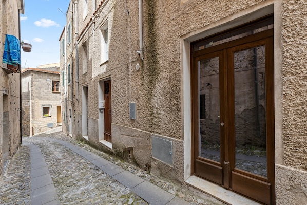 Une ruelle pavée étroite, bordée de bâtiments historiques dotés de grandes portes en bois et de petites fenêtres.