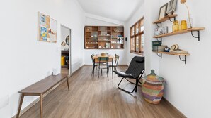 Una habitación con una mesa de comedor de madera, sillas, una silla negra, una estantería y una cesta grande de mimbre.