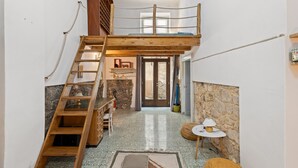 Dormitorio tipo loft con una escalera de madera, una cama litera, una pared de piedra y una pequeña mesa redonda con una lámpara.
