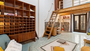 Una habitación amplia con techo alto, una estantería de madera, una escalera, un escritorio y un área de descanso acogedora.
