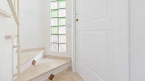 Un intérieur blanc avec un escalier, une porte et une fenêtre dotée de vitres teintées en vert.
