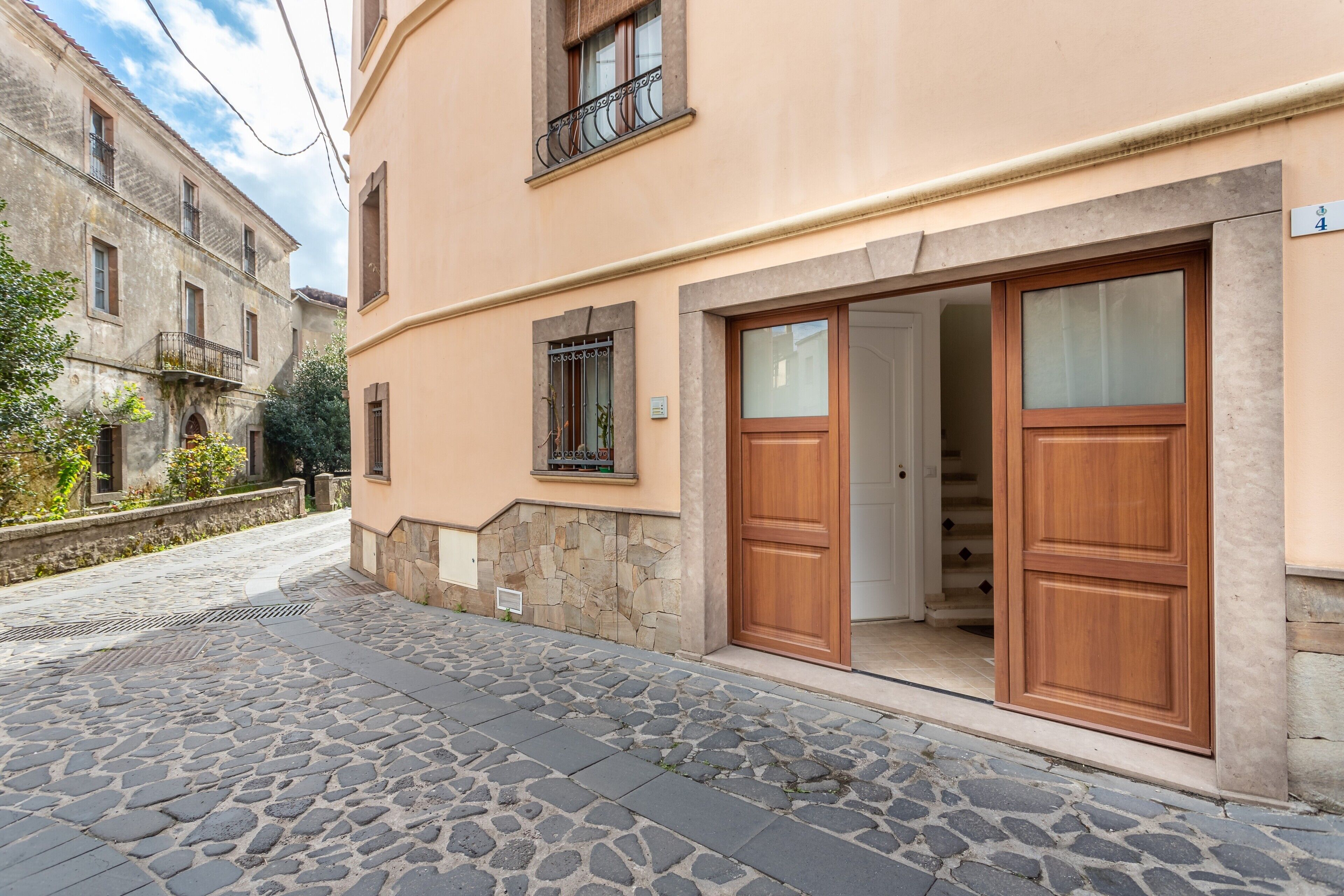A building with a stone-paved street, a wooden door, and a balcony.