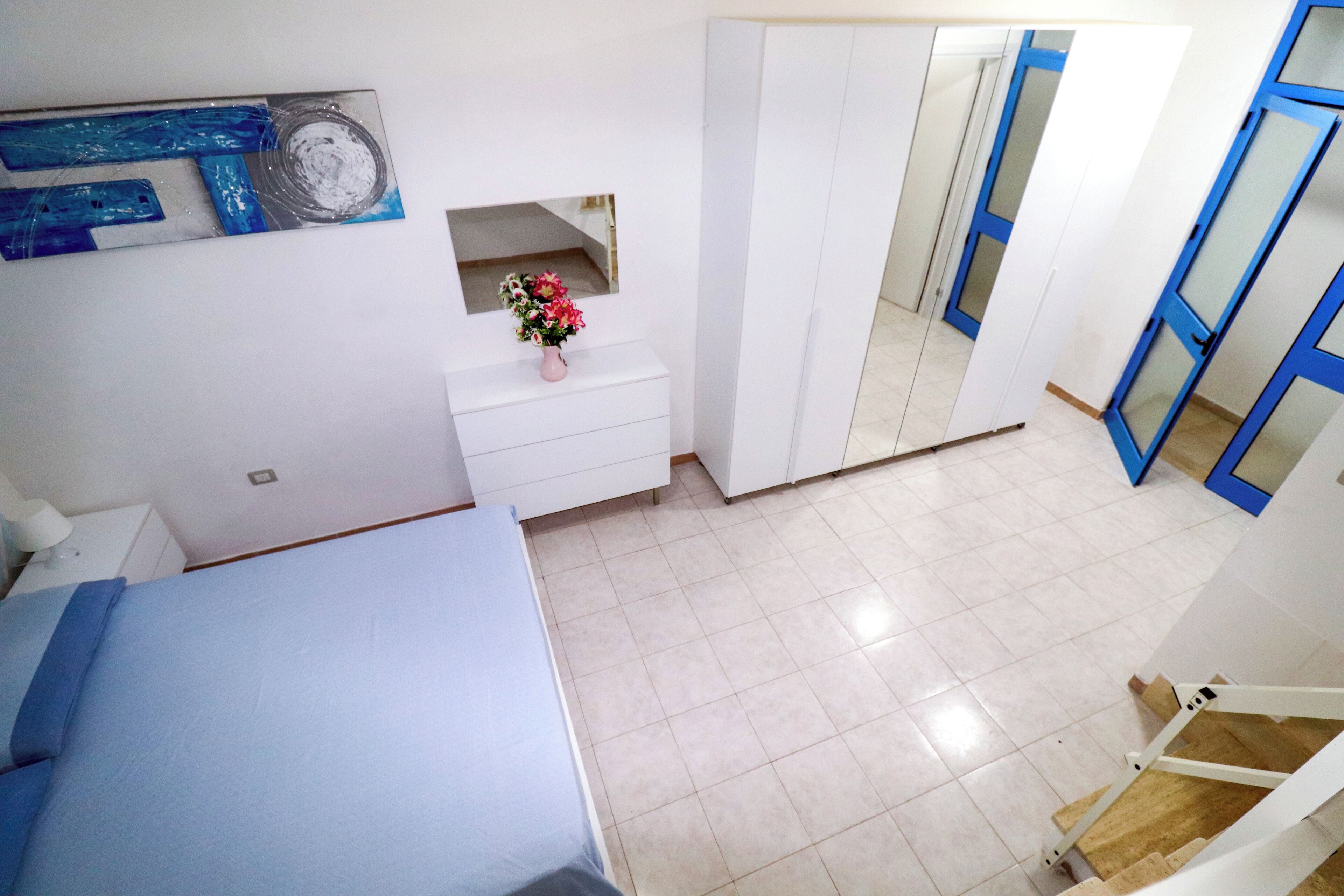 Um quarto com uma cama, penteadeira, espelho e guarda-roupa.
