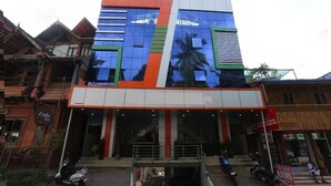 Un edificio moderno con fachada de vidrio, una cafetería en la planta baja y un letrero que dice "NARK HOME STAY".
