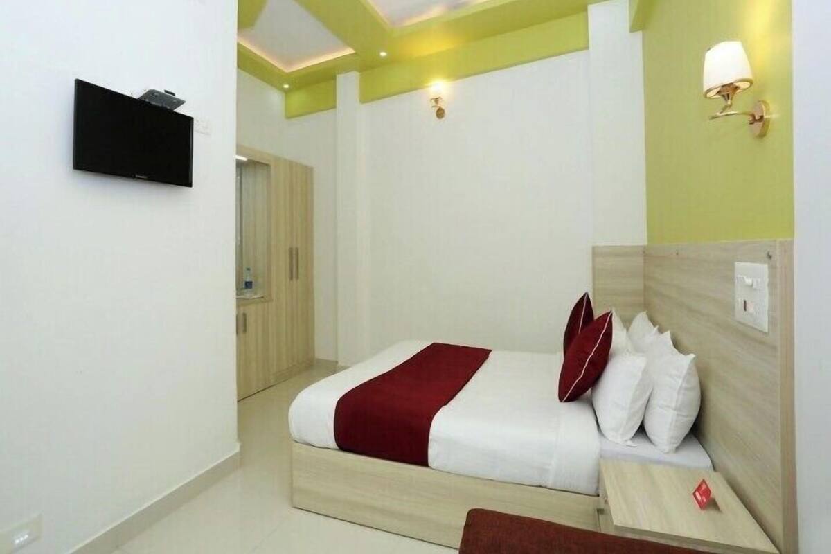 A bedroom with a bed, bedside table, and a TV mounted on the wall.