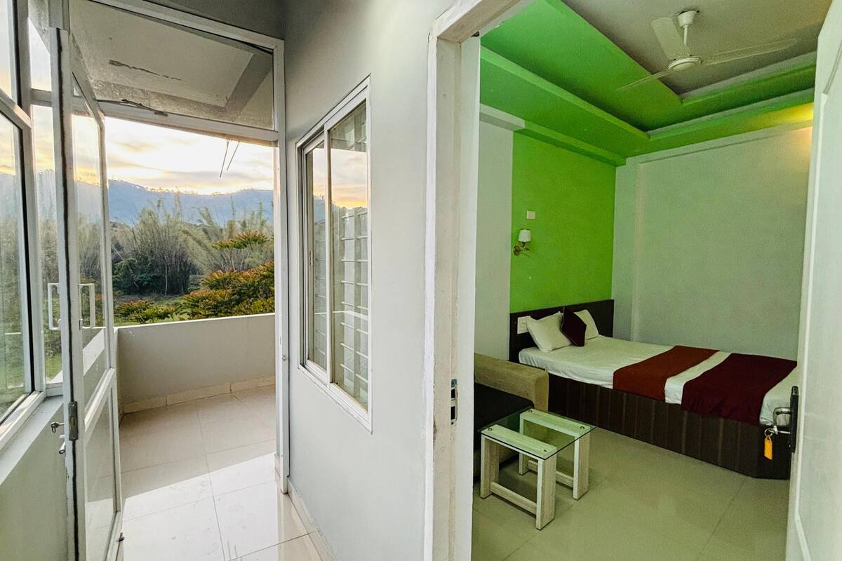 A room with a bed, a small table, and a view of the outdoors.