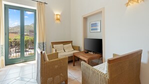 A room with a sofa, two wicker chairs, a TV, and a table. - Apartment 'La Residenza Color Del Mare' with Balcony, Wi-Fi and Air Conditioning (Bosa)