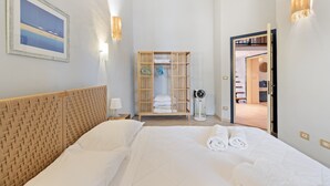 A hotel room with a bed, a wardrobe, a bedside table, and a wall-mounted lamp. - Apartment 'La Residenza Color Del Mare' with Balcony, Wi-Fi and Air Conditioning (Bosa)