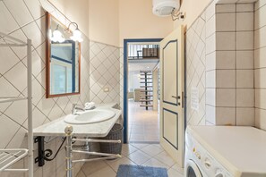 Une petite salle de bain équipée d’un lavabo, d’un miroir et d’un lave-linge.