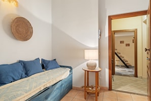 Un dormitorio con cama, almohadas, una lámpara y un tapiz de pared tejido.