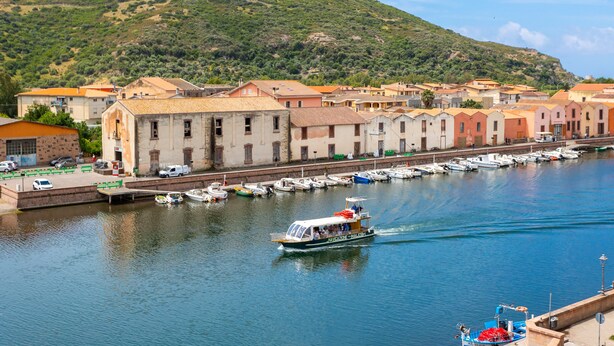 A coastal town with a marina, boats, and buildings along the waterfront.