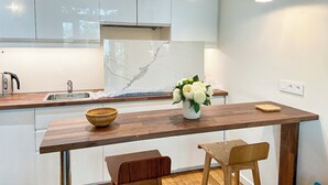 A modern kitchen with white cabinets, a marble backsplash, wooden countertops, and pendant lighting.