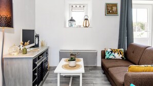 Un salón moderno con una mesa blanca, un sofá marrón y una ventana decorada.