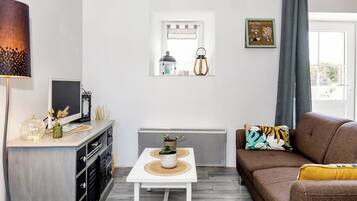 Un salon moderne avec une table blanche, un canapé marron et une fenêtre agrémentée d’objets décoratifs.
