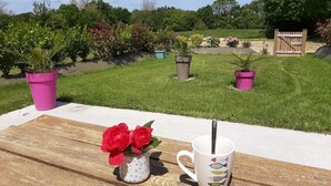 Una mesa de madera con una taza blanca y un pequeño jarrón de flores rojas.