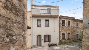 A narrow street with stone buildings, a small balcony, and a door with a window.