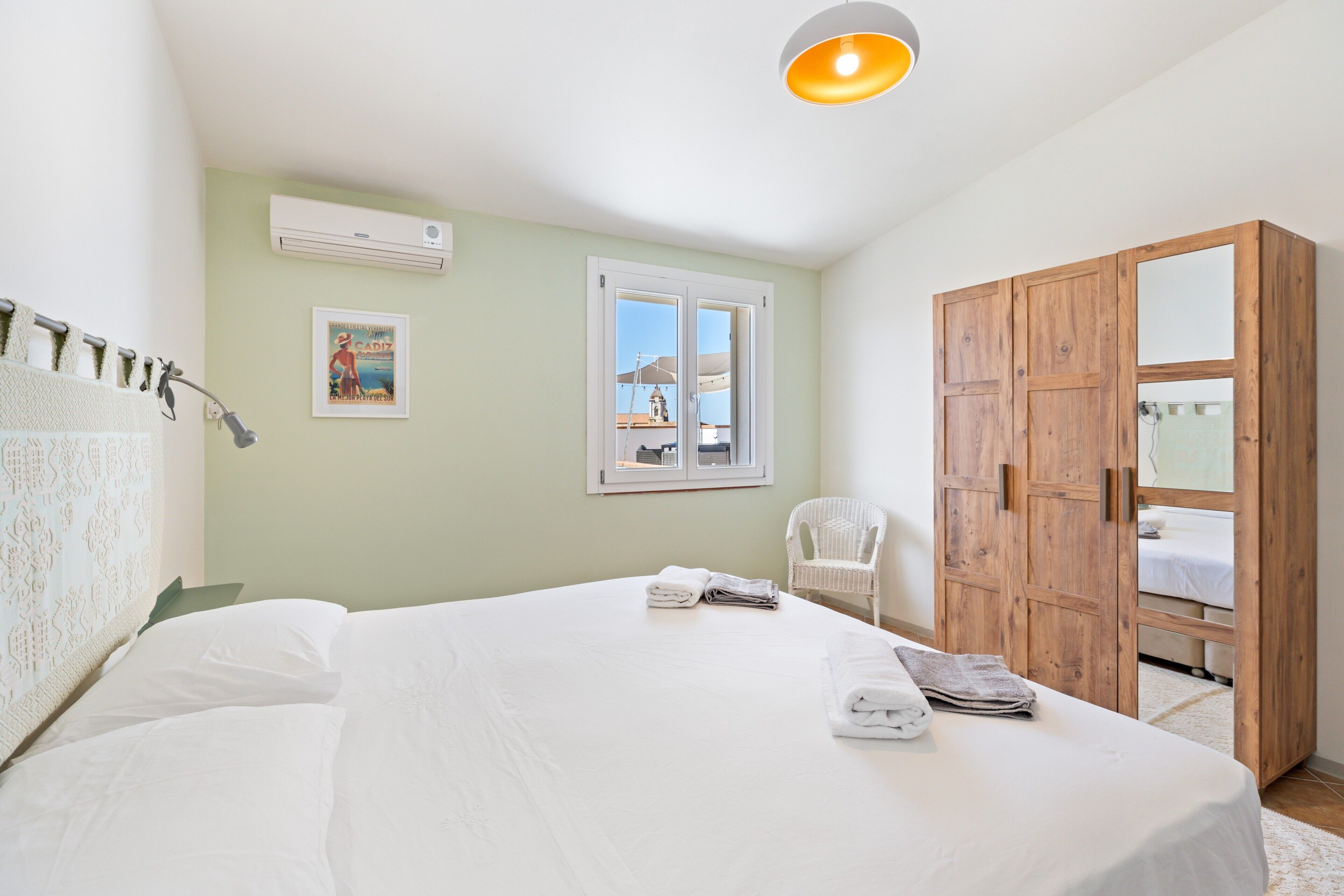 A bedroom with a bed, a wardrobe, a chair, and a window.