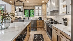 A modern kitchen with a large island, built-in appliances, and a stone accent wall.