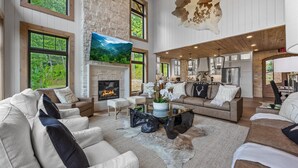 A spacious living room with a fireplace, large windows, and a stone wall.