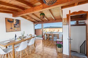A dining area with a wooden table, white chairs, and a view of the outdoors.