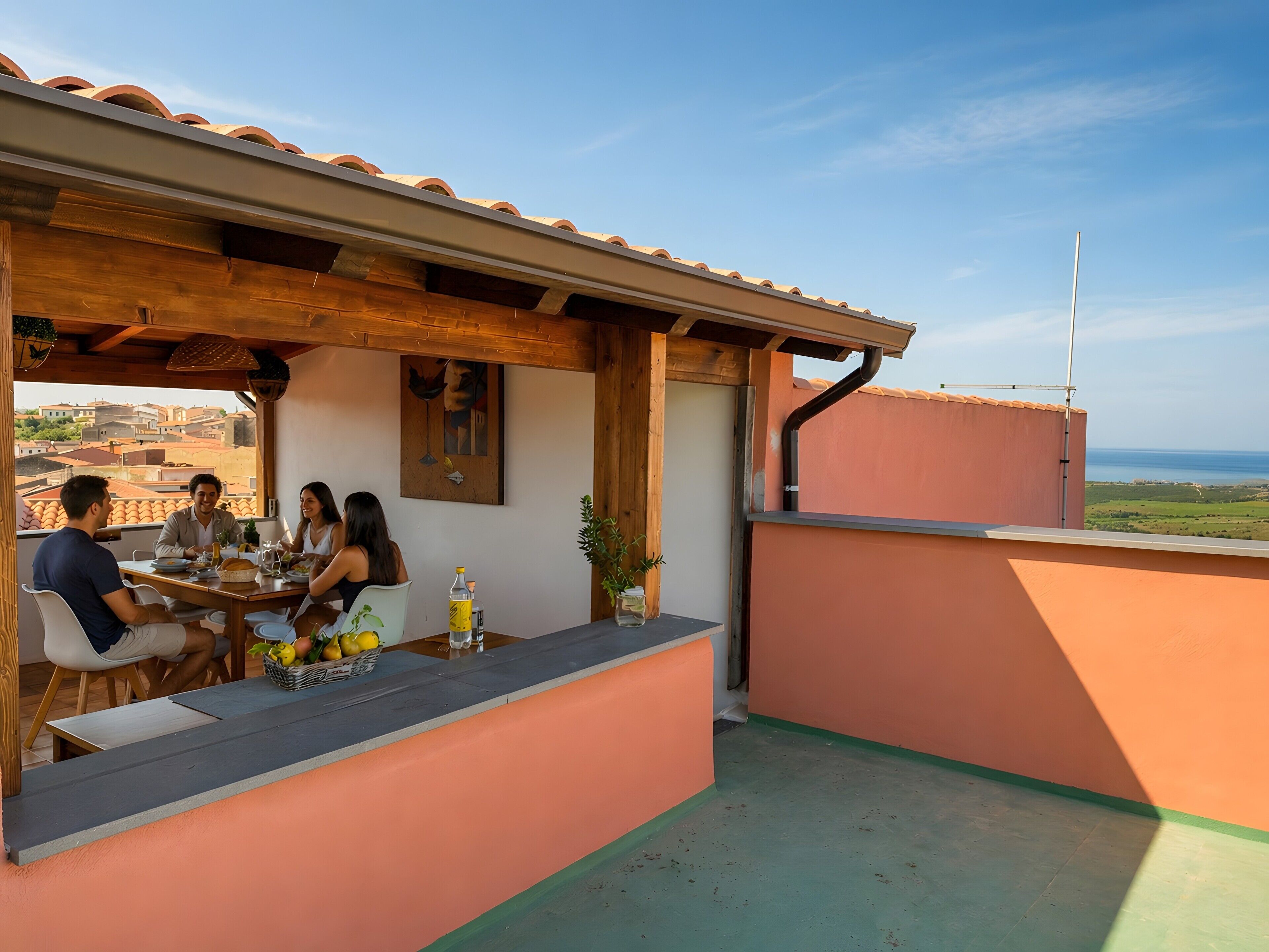 A terrace with a table set for four people, a painting on the wall, and a view of the sea.
