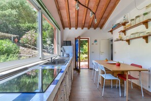 A kitchen with a glass backsplash, wooden ceiling beams, and a dining area with a wooden table and chairs.
