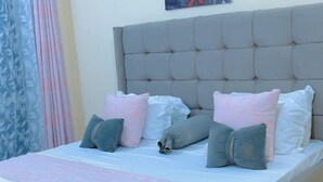 A bedroom with a tufted headboard, a bed with multiple pillows, and a bedside table.