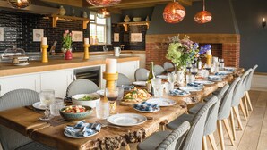 A long wooden dining table set for a meal, with chairs on both sides. - Wilderness Reserve - The Grange (Halesworth)