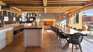 A modern kitchen with wooden beams, a central island, and hanging pendant lights. - Wilderness Reserve - The Grange (Halesworth)