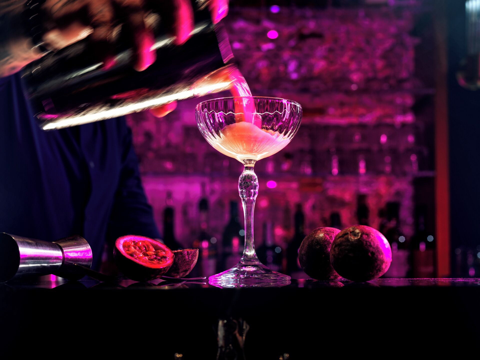 A bartender pouring a drink into a martini glass.