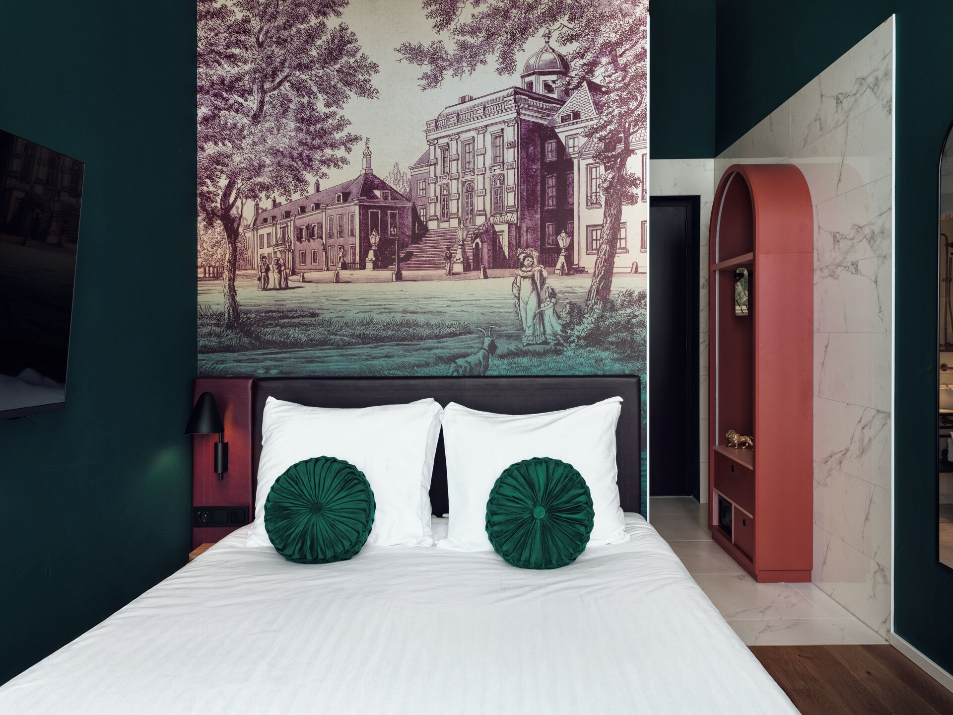 Un dormitorio con una cama grande, dos almohadas verdes, un cabecero con un mural, una estantería roja en arco y una pared de mármol.