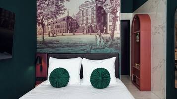 Un dormitorio con una cama grande, dos almohadas verdes, un cabecero con un mural, una estantería roja en arco y una pared de mármol.