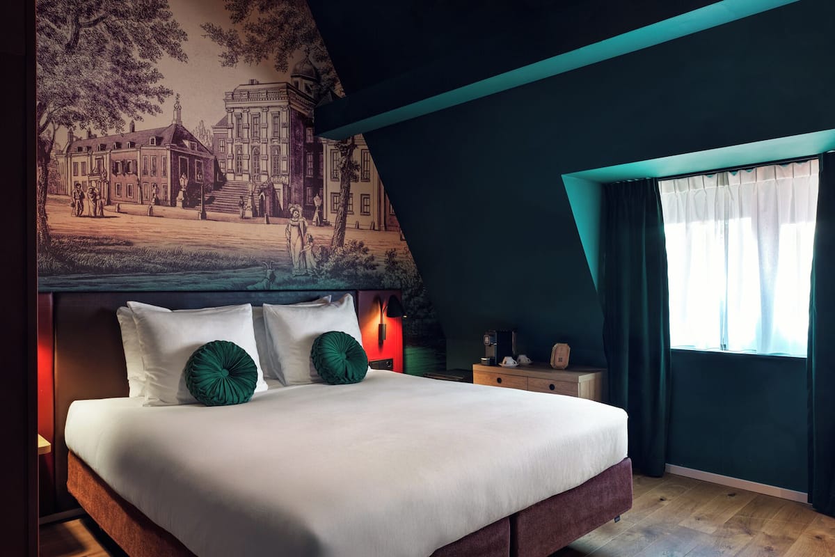 A modern bedroom with a large bed, a mural on the wall, and a window with curtains.
