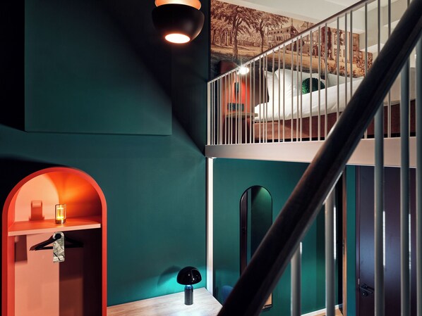 Un interior moderno con una escalera, una cama en el nivel superior y una lámpara original en el nivel inferior.