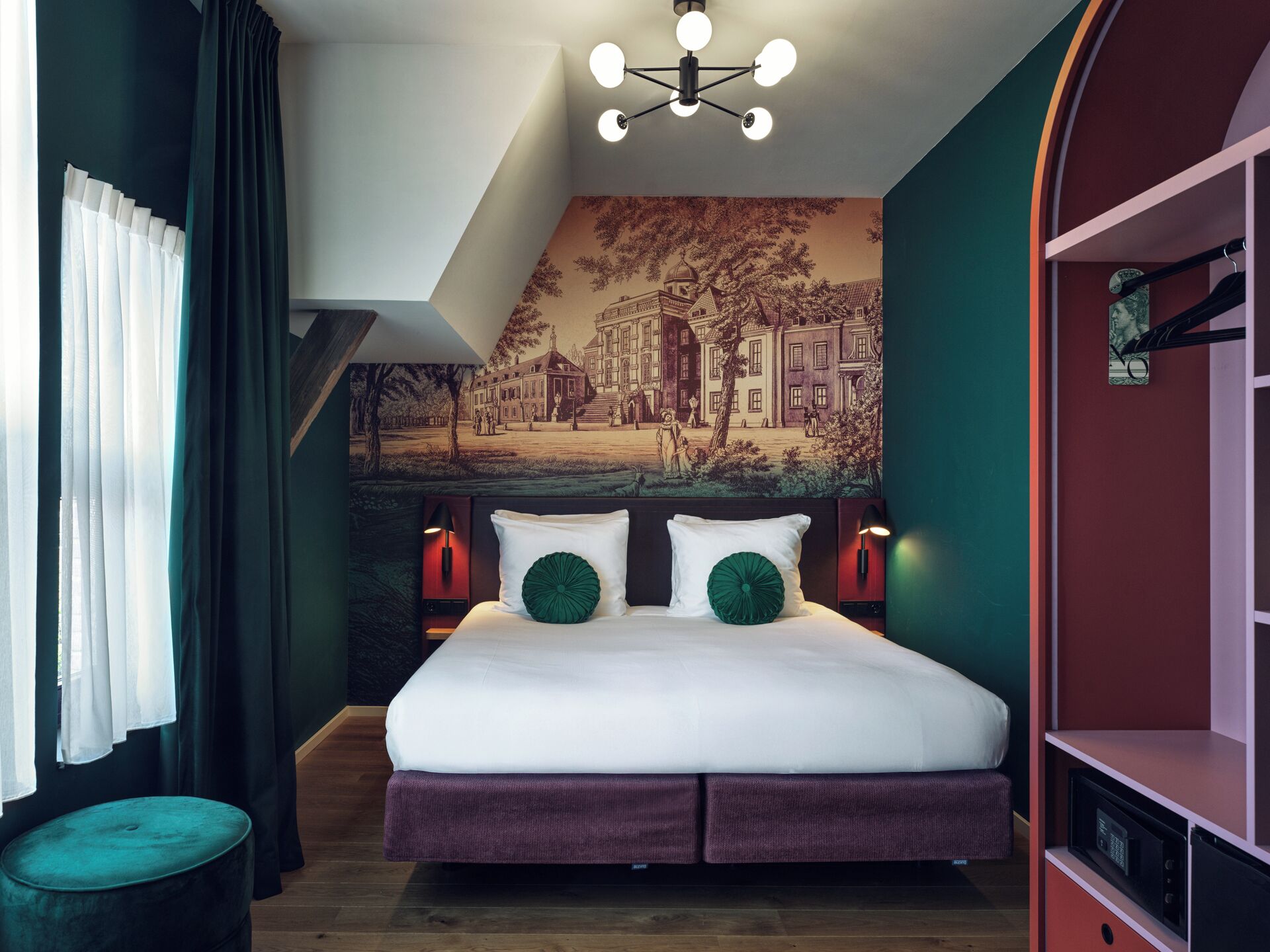 A modern bedroom with a large bed, two bedside lamps, a mural on the wall, and a red shelving unit.
