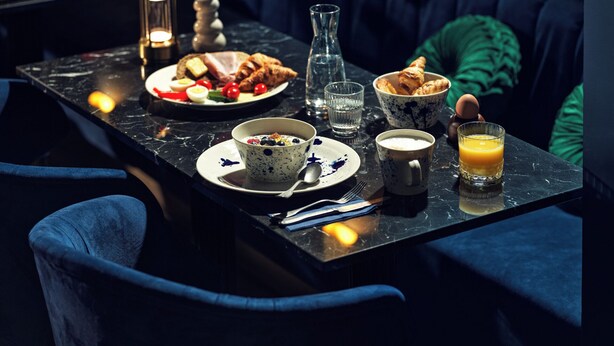 Frühstücksaufteilung mit Croissants, Eiern und einer Schüssel Joghurt auf einem Marmortisch.
