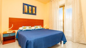 Un dormitorio con cabecera de madera, colcha azul y mesita de noche con lámpara.