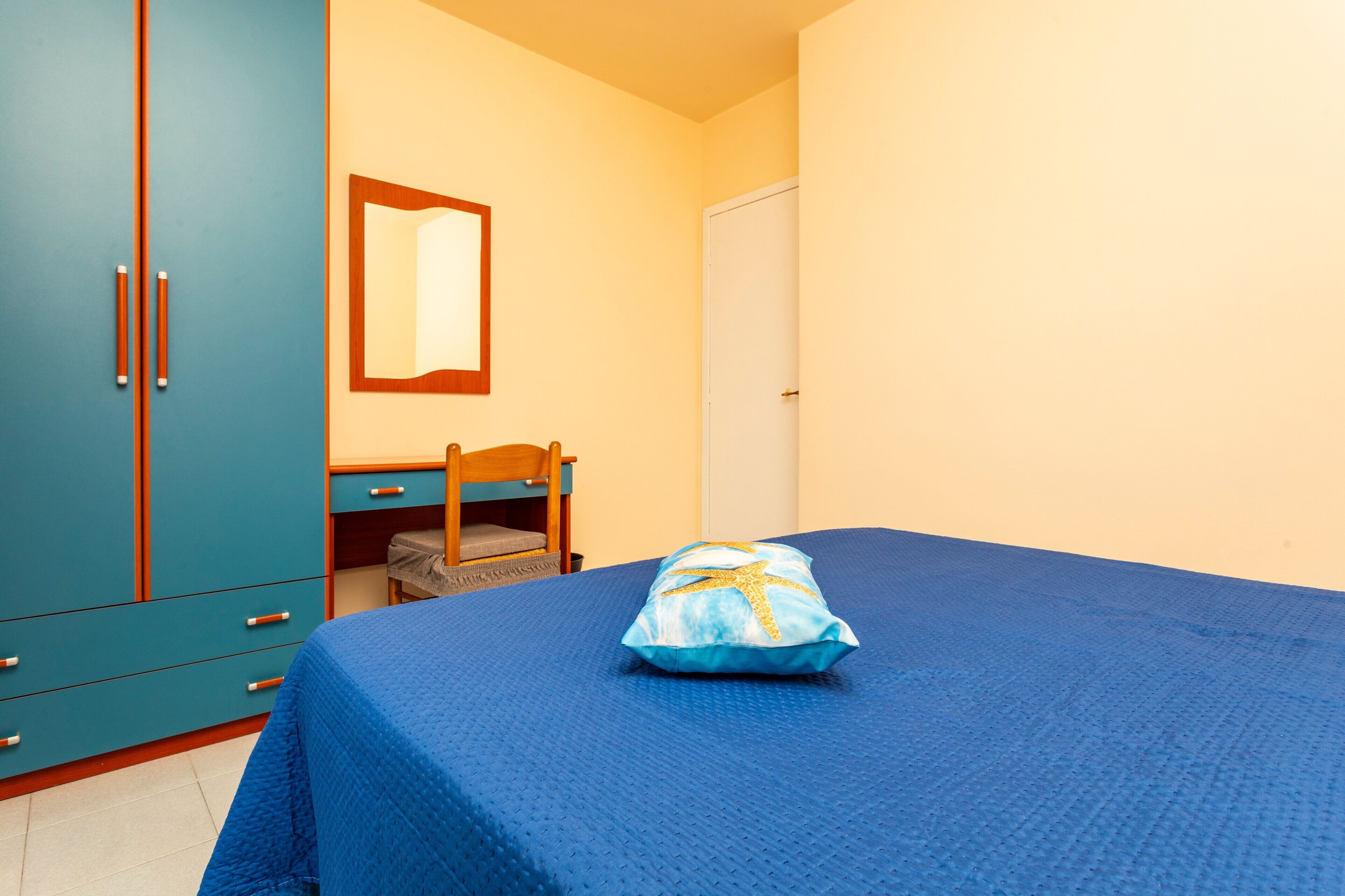 Une chambre avec un lit, un bureau, une chaise et une armoire.