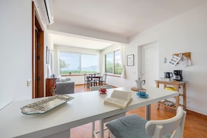A modern living room with a dining area, large windows, and a view of the outdoors.