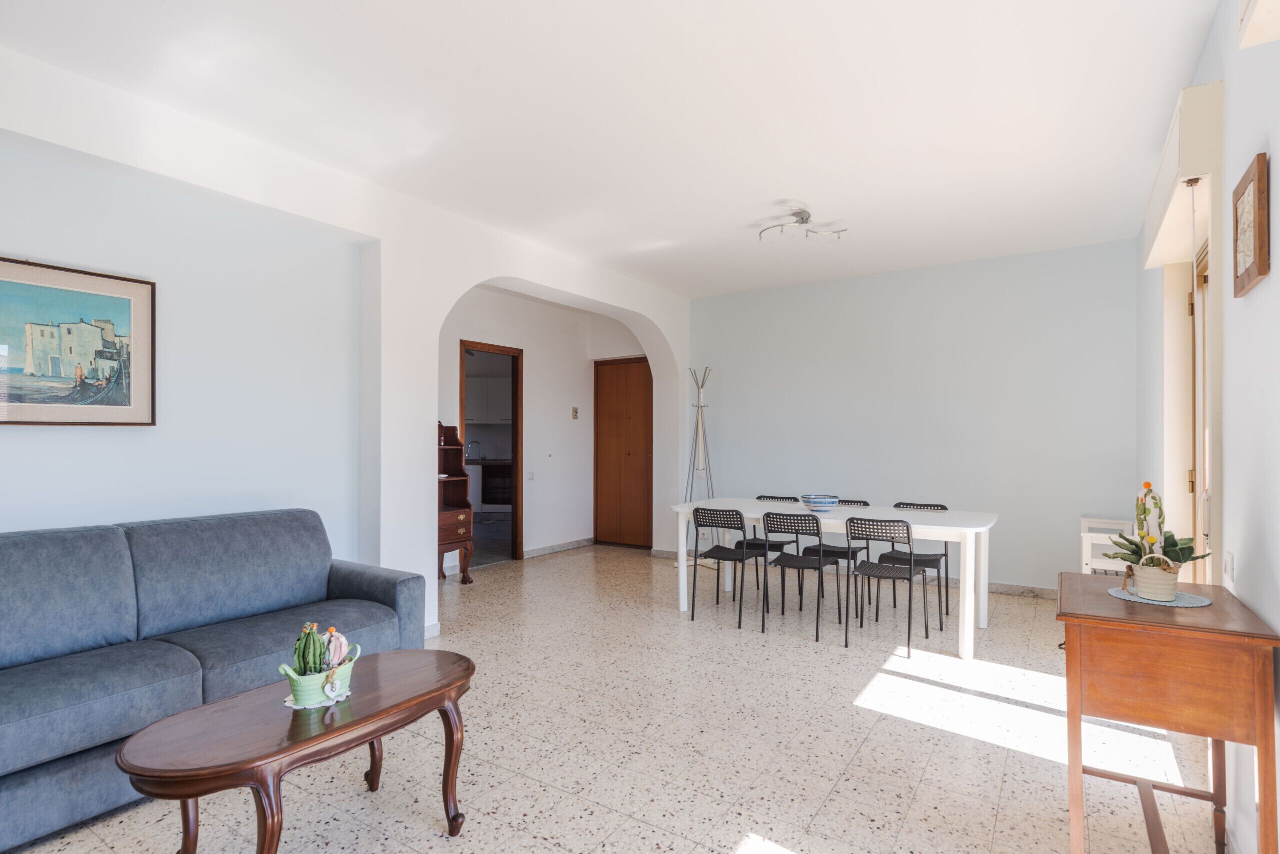 Un soggiorno con un divano, un tavolino, un tavolo da pranzo con sedie e una zona cucina sullo sfondo.