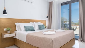 Een moderne slaapkamer met een houten hoofdbord, een nachtkastje met een plant, een groot bed met een beige deken, en uitzicht op de omgeving via een schuifdeur.