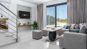 Een moderne woonkamer met een flatscreen televisie, een trap, een bank en uitzicht op de omgeving.