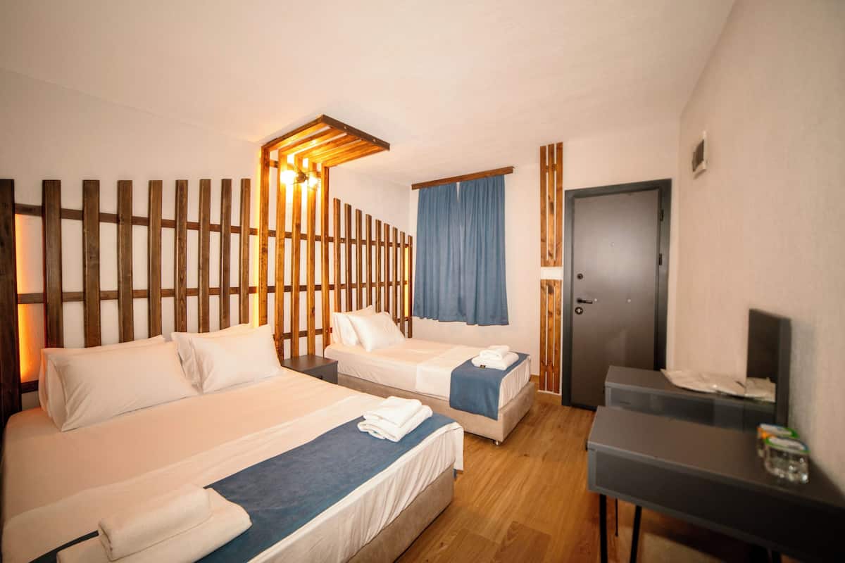 Ein Hotelzimmer mit zwei Betten, einem Schreibtisch und einem Kleiderschrank.