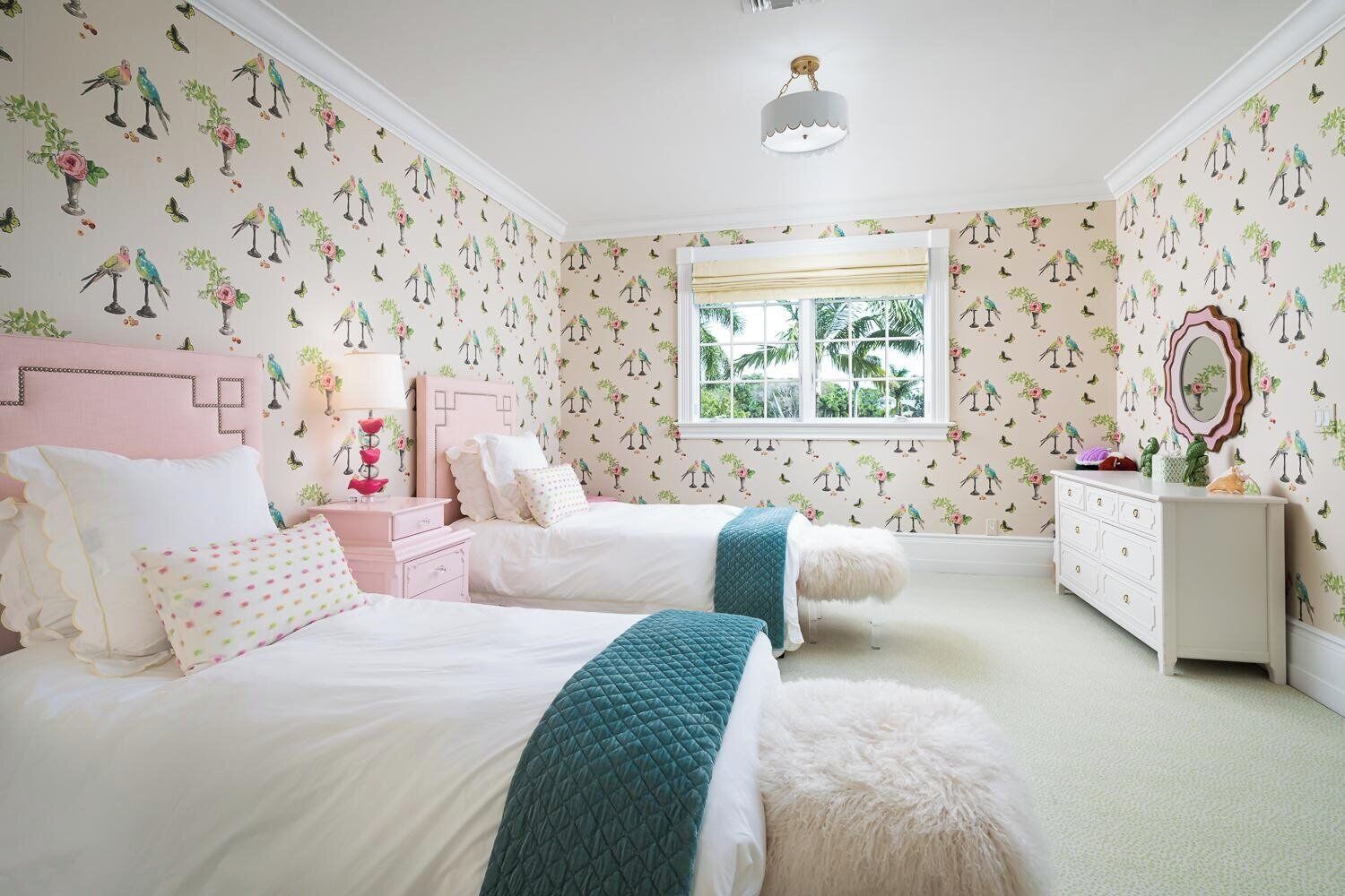 Une chambre avec deux lits, une commode et une fenêtre donnant sur un paysage verdoyant.