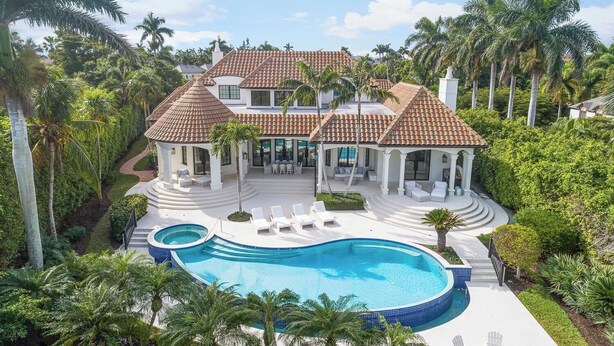 A large house with a swimming pool, surrounded by palm trees and lush greenery. - Port Royal - Sweeping Lake Views (Naples)